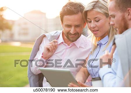 Businesspeople using digital tablet at park on sunny day View Large Photo Image Stock Image - Businesspeople using digital tablet at park on sunny day. Fotosearch