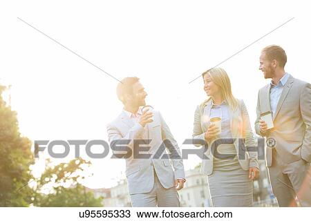 Businesspeople with disposable cups conversing against clear sky on sunny day View Large Photo Image Stock Image - Businesspeople with disposable cups conversing against clear sky on sunny day. Fotosearch