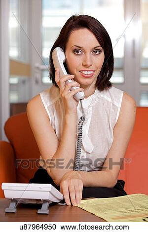 Stock Image - Businesswoman conversing on landline phone. Fotosearch