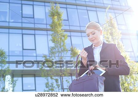 Businesswoman putting digital tablet in purse on sunny day View Large Photo Image Stock Image - Businesswoman putting digital tablet in purse on sunny day. Fotosearch