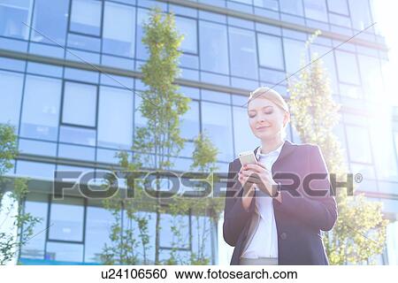 Businesswoman text messaging through cell phone on sunny day View Large Photo Image Stock Image - Businesswoman text messaging through cell phone on sunny day. Fotosearch