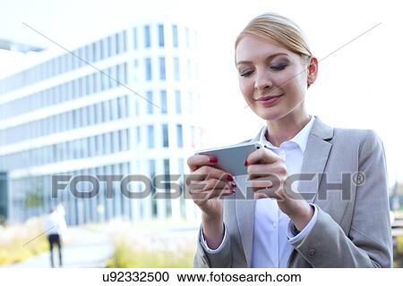 Businesswoman text messaging through smart phone outdoors View Large Photo Image Stock Image - Businesswoman text messaging through smart phone outdoors. Fotosearch