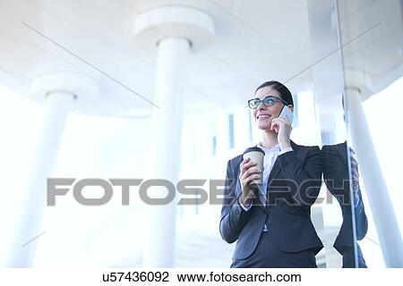Businesswoman using cell phone while holding disposable cup outdoors View Large Photo Image Stock Image - Businesswoman using cell phone while holding disposable cup outdoors. Fotosearch