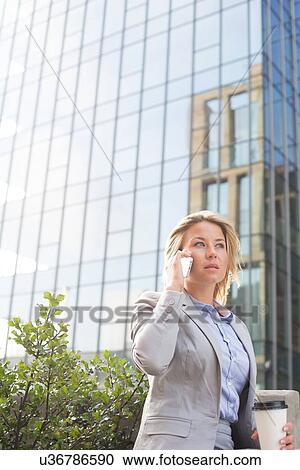 Businesswoman using mobile phone outside office building View Large Photo Image Stock Image - Businesswoman using mobile phone outside office building. Fotosearch