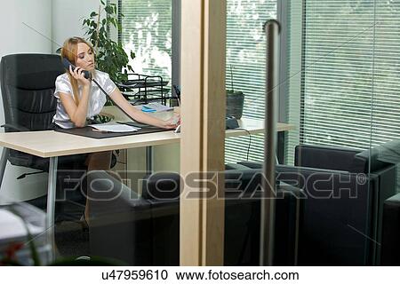 Stock Image - Businesswoman using phone at office. Fotosearch