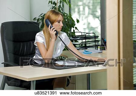 Stock Image - Businesswoman using phone at office. Fotosearch
