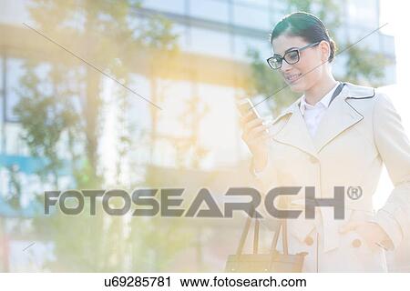 Businesswoman using smart phone on sunny day View Large Photo Image Stock Image - Businesswoman using smart phone on sunny day. Fotosearch