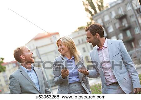 Stock Photo - Cheerful businesspeople walking in city. Fotosearch