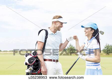 Stock Image - Cheerful friends giving high-five at golf course. Fotosearch