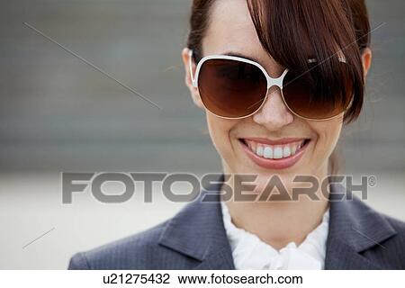 Close-up of a young woman wearing sunglasses View Large Photo Image Stock Image - Close-up of a young woman wearing sunglasses. Fotosearch
