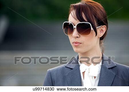 Close-up of a young woman wearing sunglasses View Large Photo Image Stock Image - Close-up of a young woman wearing sunglasses. Fotosearch