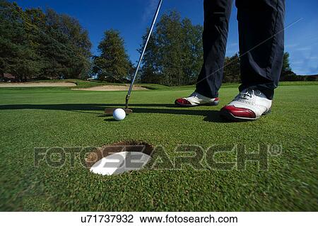 Close up of person putting golf ball on golf course View Large Photo Image Stock Image - Close up of person putting golf ball on golf course. Fotosearch