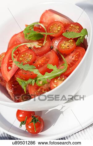 Stock Photograph - Close - up of sliced tomatoes with rucola. Fotosearch