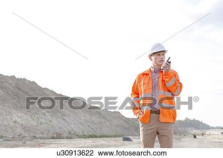 Confident male supervisor using walkie-talkie on construction site against clear sky View Large Photo Image Stock Image - Confident male supervisor using walkie-talkie on construction site against clear sky. Fotosearch