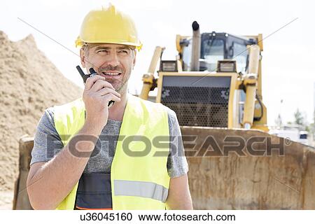 Confident supervisor using walkie-talkie at construction site View Large Photo Image Stock Image - Confident supervisor using walkie-talkie at construction site. Fotosearch