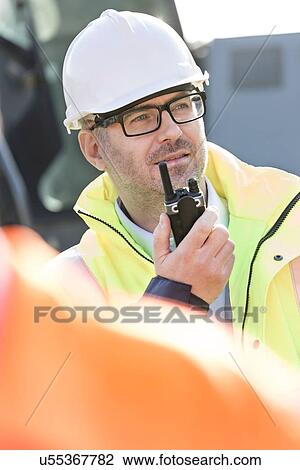 Confident supervisor using walkie-talkie at construction site View Large Photo Image Stock Image - Confident supervisor using walkie-talkie at construction site. Fotosearch