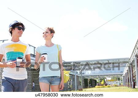 Couple holding disposable cups while walking at park View Large Photo Image Stock Image - Couple holding disposable cups while walking at park. Fotosearch