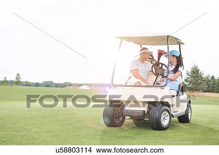 Couple looking at each other while sitting in golf cart against clear sky View Large Photo Image Picture - Couple looking at each other while sitting in golf cart against clear sky. Fotosearch