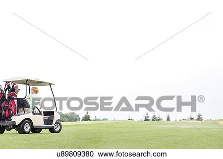 Couple sitting in golf cart against clear sky View Large Photo Image Stock Image - Couple sitting in golf cart against clear sky. Fotosearch