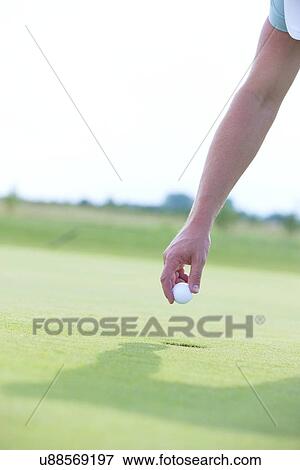 Stock Photo - Cropped image of hand holding golf ball. Fotosearch