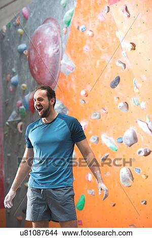 Picture - Dedicated man shouting by climbing wall in crossfit gym. Fotosearch