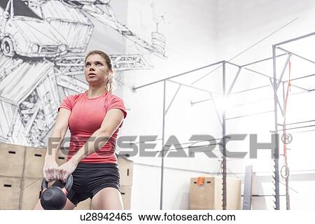 Dedicated woman lifting kettlebell in crossfit gym View Large Photo Image Stock Photography - Dedicated woman lifting kettlebell in crossfit gym. Fotosearch