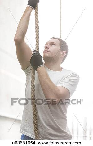 Determined man climbing rope in crossfit gym View Large Photo Image Picture - Determined man climbing rope in crossfit gym. Fotosearch