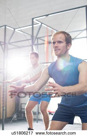 Stock Photo - Determined men exercising at crossfit gym. Fotosearch