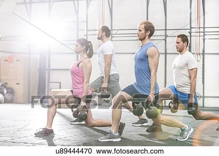 Stock Image - Determined people lifting kettlebells at crossfit gym. Fotosearch
