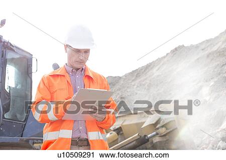 Engineer reading clipboard at construction site View Large Photo Image Stock Image - Engineer reading clipboard at construction site. Fotosearch