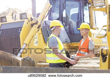 Stock Image - Engineers discussing at construction site. Fotosearch