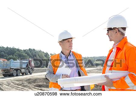 Engineers discussing at construction site against clear sky View Large Photo Image Stock Photo - Engineers discussing at construction site against clear sky. Fotosearch