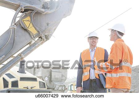 Engineers discussing at construction site against clear sky View Large Photo Image Stock Photo - Engineers discussing at construction site against clear sky. Fotosearch