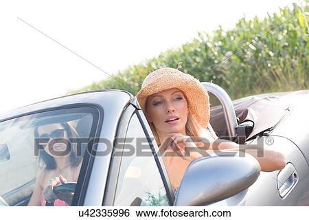 Female friends sitting in convertible on sunny day View Large Photo Image Stock Photograph - Female friends sitting in convertible on sunny day. Fotosearch