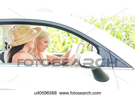 Female friends using digital tablet in car View Large Photo Image Stock Photo - Female friends using digital tablet in car. Fotosearch