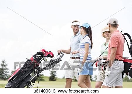 Friends communicating while walking at golf course against clear sky View Large Photo Image Stock Image - Friends communicating while walking at golf course against clear sky. Fotosearch