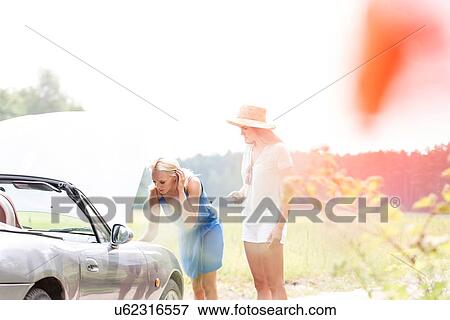 Friends repairing broken down car on sunny day View Large Photo Image Stock Photo - Friends repairing broken down car on sunny day. Fotosearch