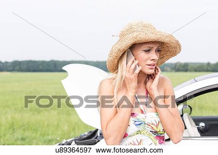 Frustrated woman using cell phone by broken down car View Large Photo Image Stock Photo - Frustrated woman using cell phone by broken down car. Fotosearch