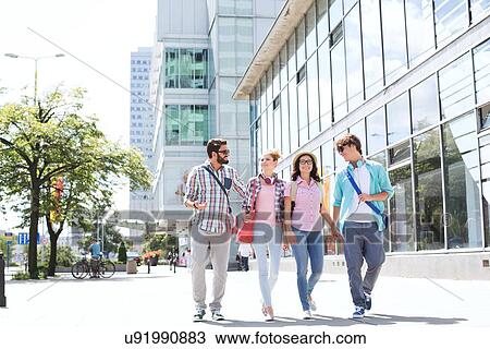 Stock Image - Full-length male and female friends walking on city street. Fotosearch