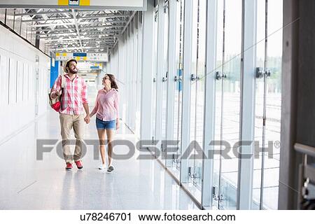 Stock Image - Full-length of couple walking in covered passage. Fotosearch