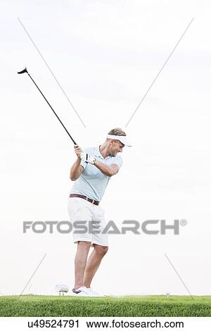 Full-length of mid-adult man swinging golf club against clear sky View Large Photo Image Stock Image - Full-length of mid-adult man swinging golf club against clear sky. Fotosearch
