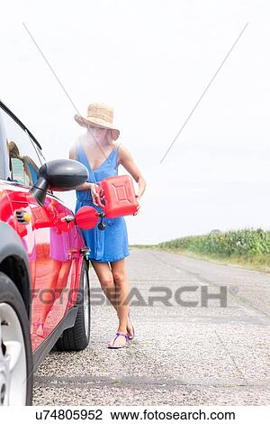 Full-length of woman refueling car on country road against clear sky View Large Photo Image Stock Image - Full-length of woman refueling car on country road against clear sky. Fotosearch