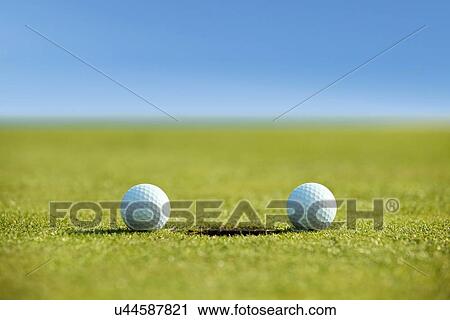 Stock Image - Golf balls near hole. Fotosearch