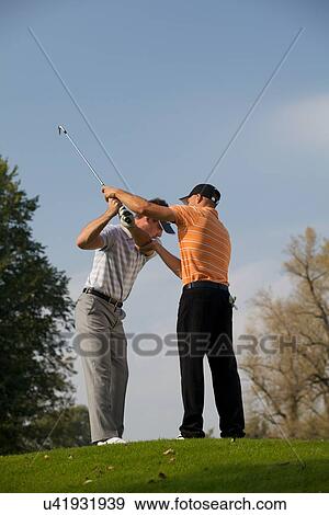 Golf professional helping young man with his swing View Large Photo Image Stock Photo - Golf professional helping young man with his swing. Fotosearch
