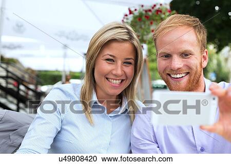 Happy business couple taking selfie at outdoor restaurant View Large Photo Image Stock Image - Happy business couple taking selfie at outdoor restaurant. Fotosearch