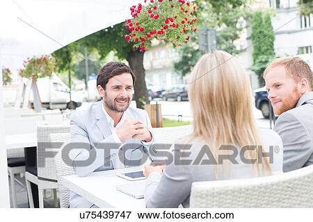 Happy businessman discussing with colleagues at sidewalk cafe View Large Photo Image Stock Photo - Happy businessman discussing with colleagues at sidewalk cafe. Fotosearch