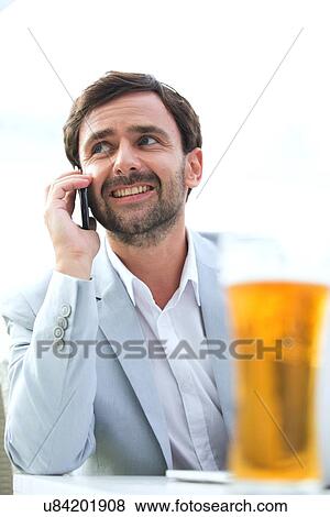 Happy businessman looking away while using mobile phone at outdoor restaurant View Large Photo Image Stock Photo - Happy businessman looking away while using mobile phone at outdoor restaurant. Fotosearch