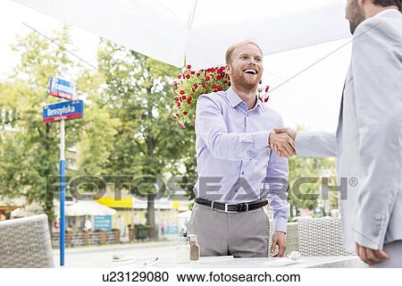 Happy businessmen shaking hands at outdoor restaurant View Large Photo Image Stock Image - Happy businessmen shaking hands at outdoor restaurant. Fotosearch
