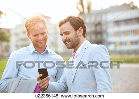 Stock Photography - Happy businessmen using mobile phone in city. Fotosearch