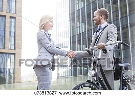 Happy businesspeople shaking hands outside office building View Large Photo Image Stock Photo - Happy businesspeople shaking hands outside office building. Fotosearch